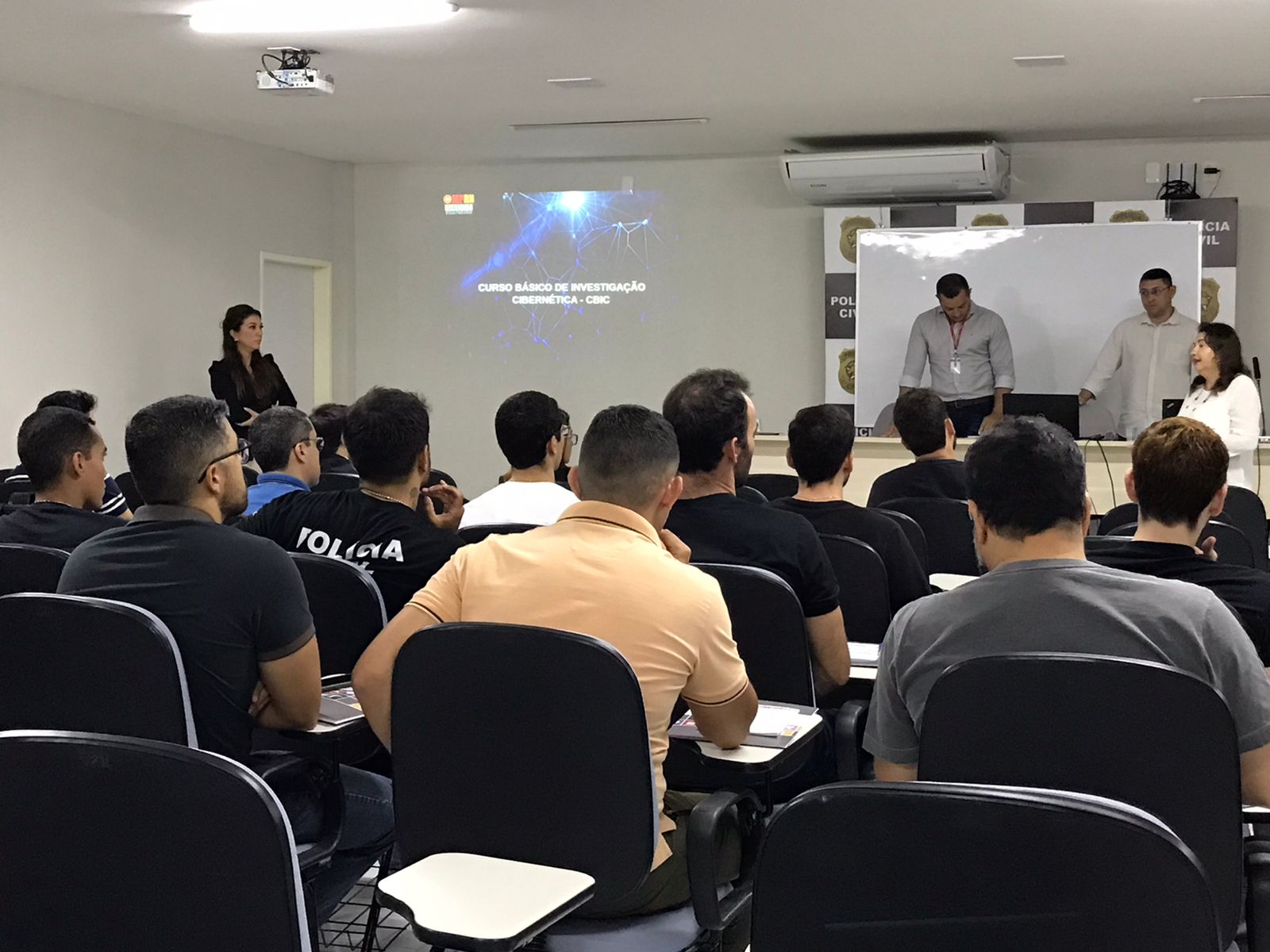 Imagem de pessoas sentadas em um auditório, participando de um curso.