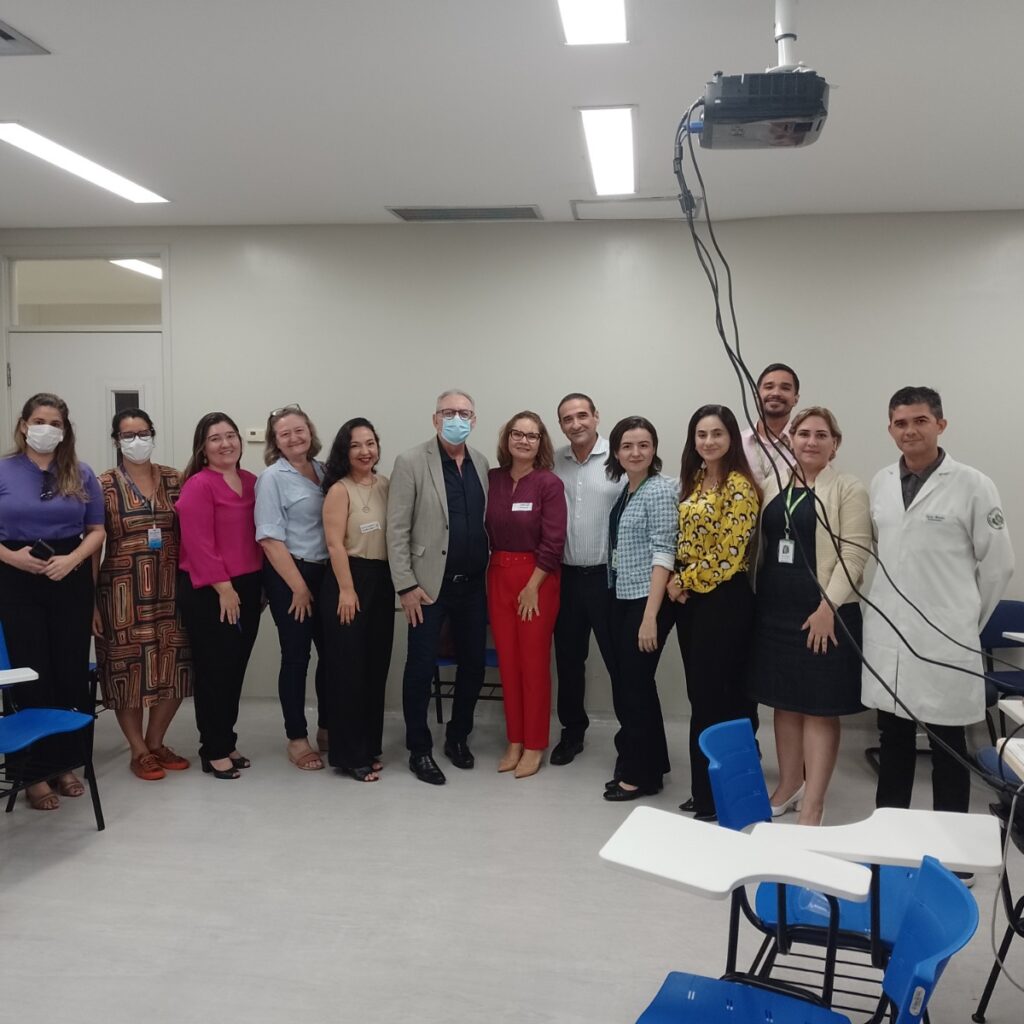 Imagem de 13 pessoas, em pé, uma ao lado da outra, em uma sala, posando para uma foto.