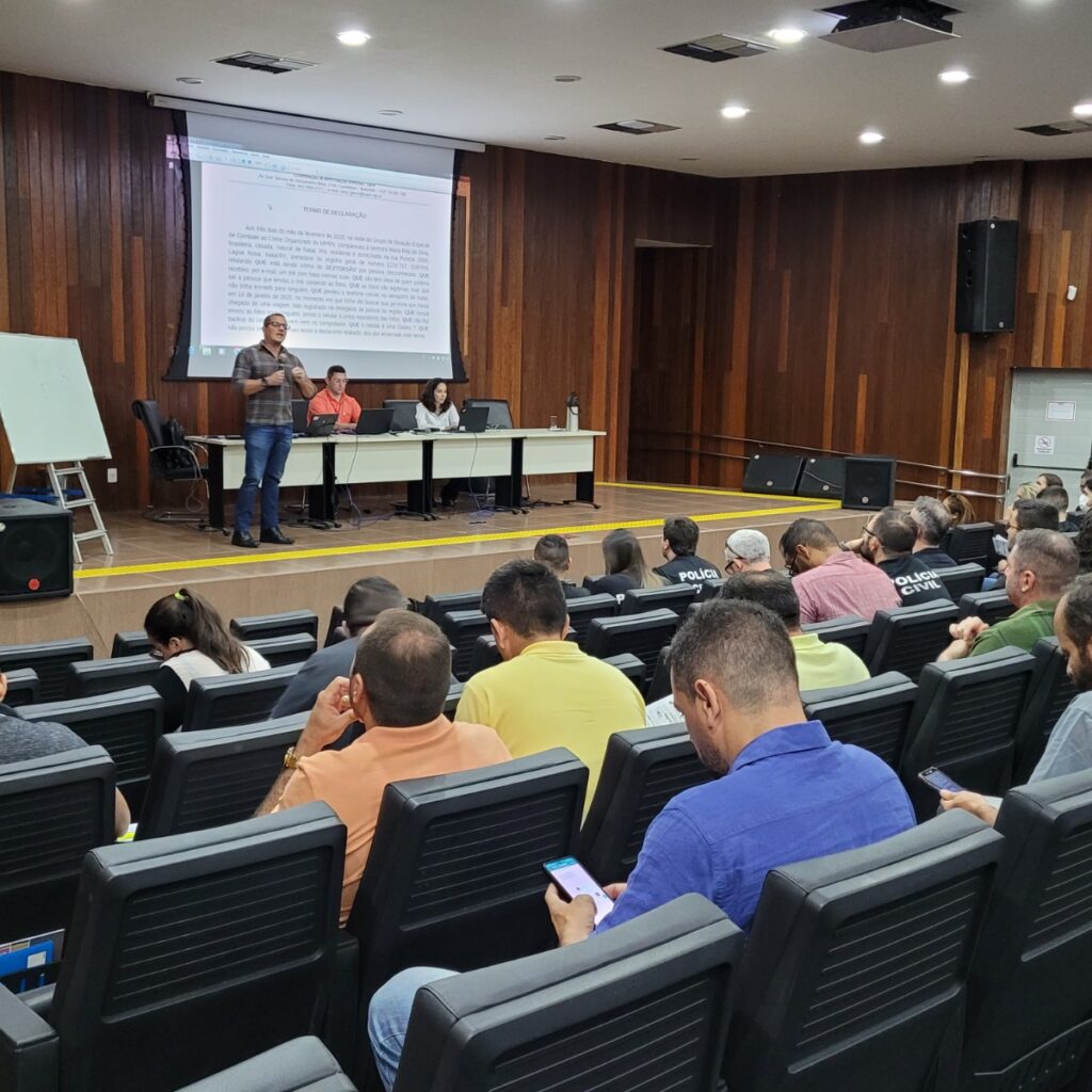 Imagem de um auditório com várias pessoas, assistindo a uma palestra.