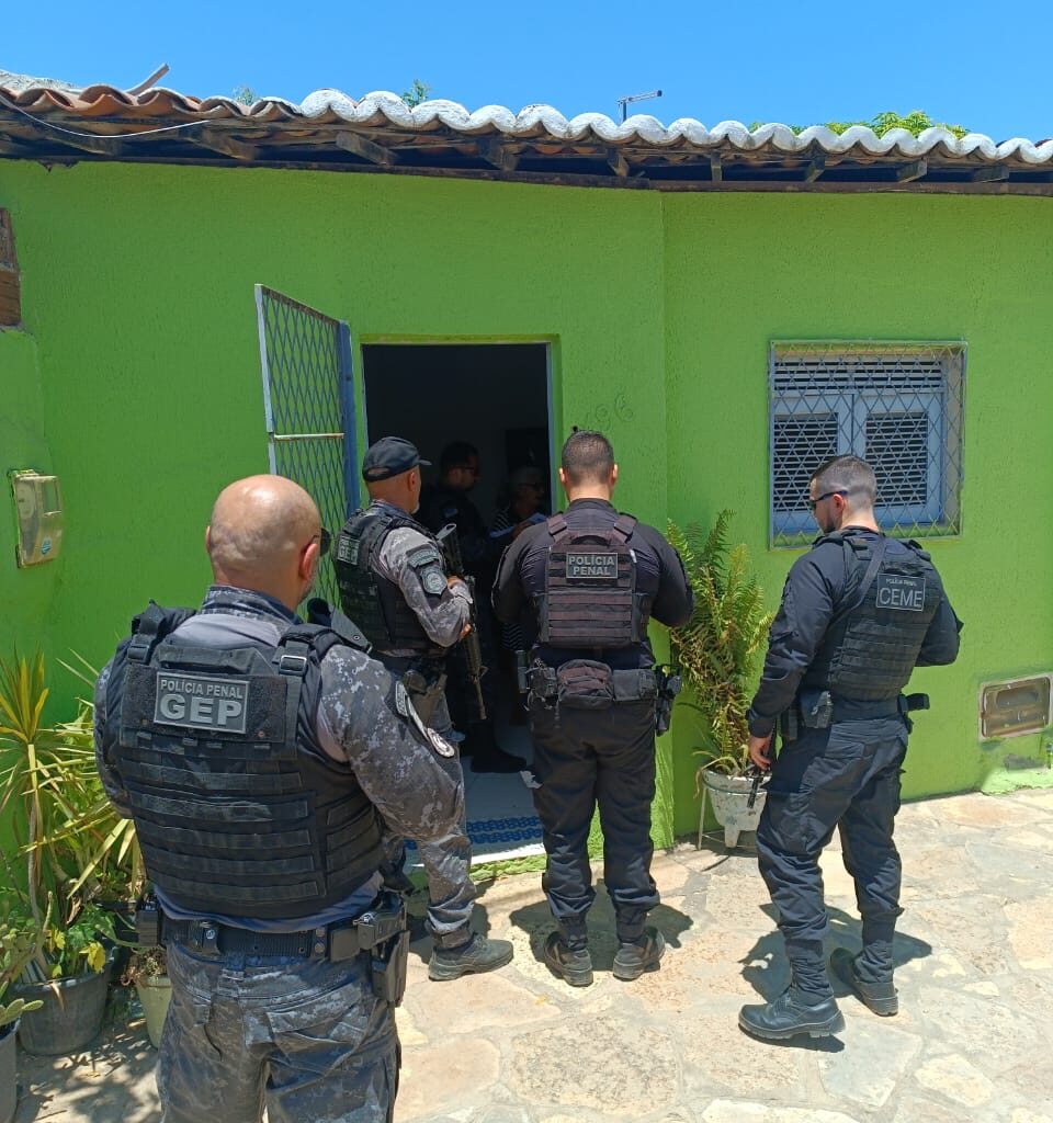 Imagens de quatro policiais militares em frente a uma residência, durante a operação Home Care.