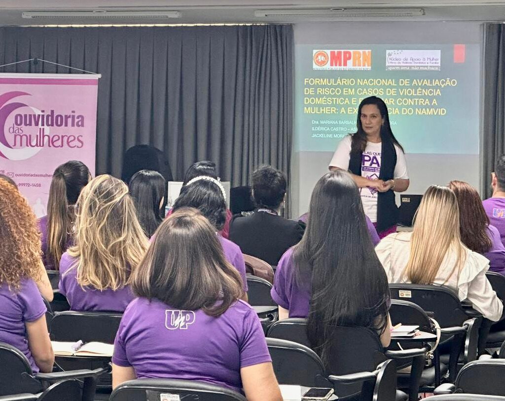 Imagem da promotora de Justiça Mariana Barbalho, palestrando para uma plateia de estudantes de Direito, em um auditório.