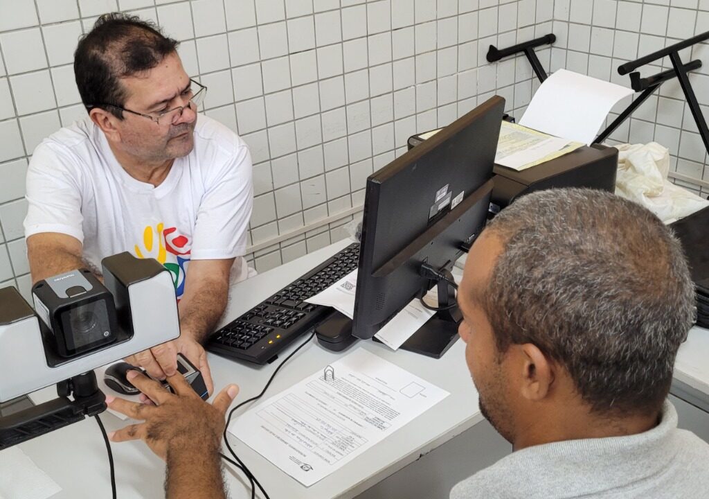 Imagem de uma pessoa em situação de rua tendo as digitais colhidas para a emissão de RG