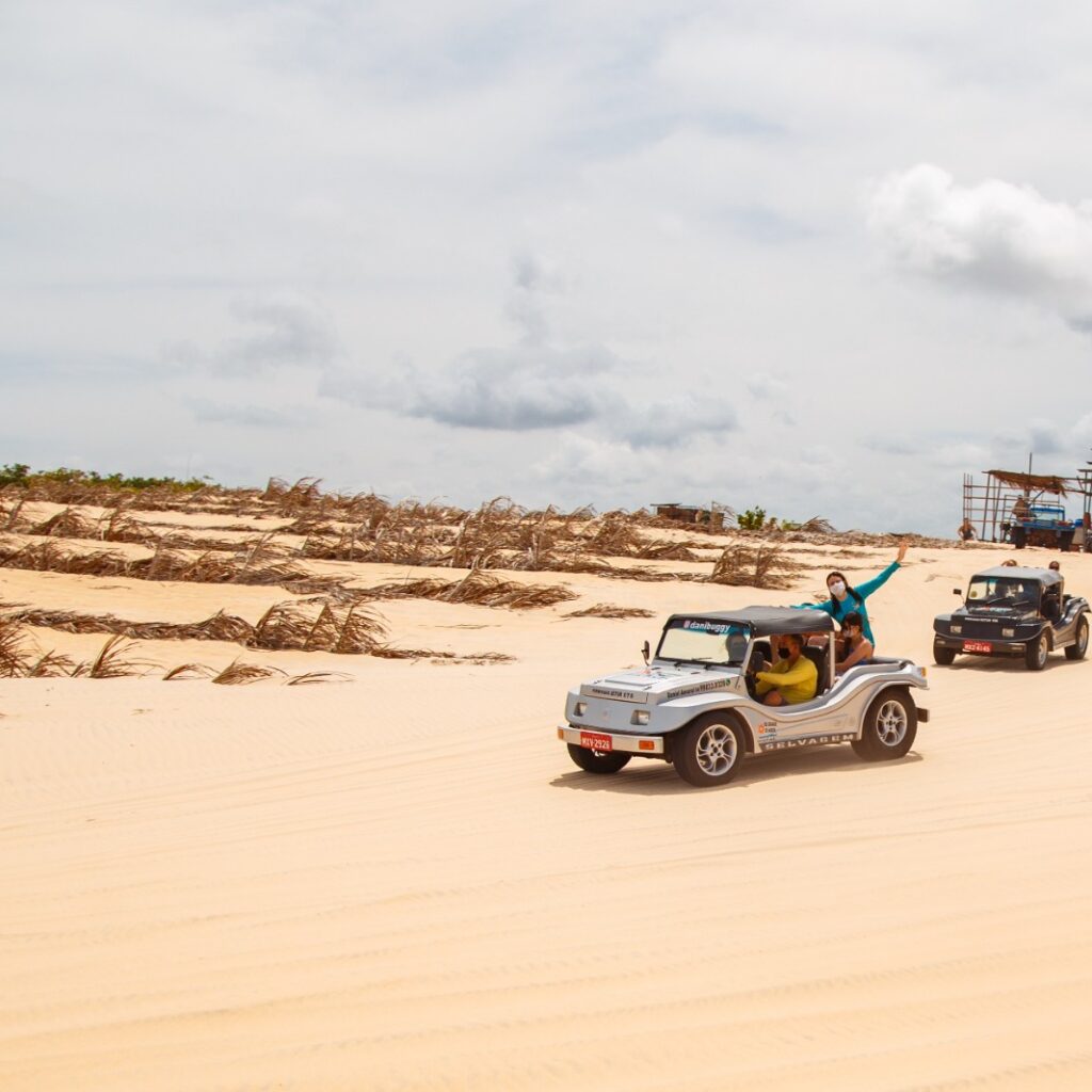 Imagem de buggy com turistas fazendo passeio sobre uma duna.