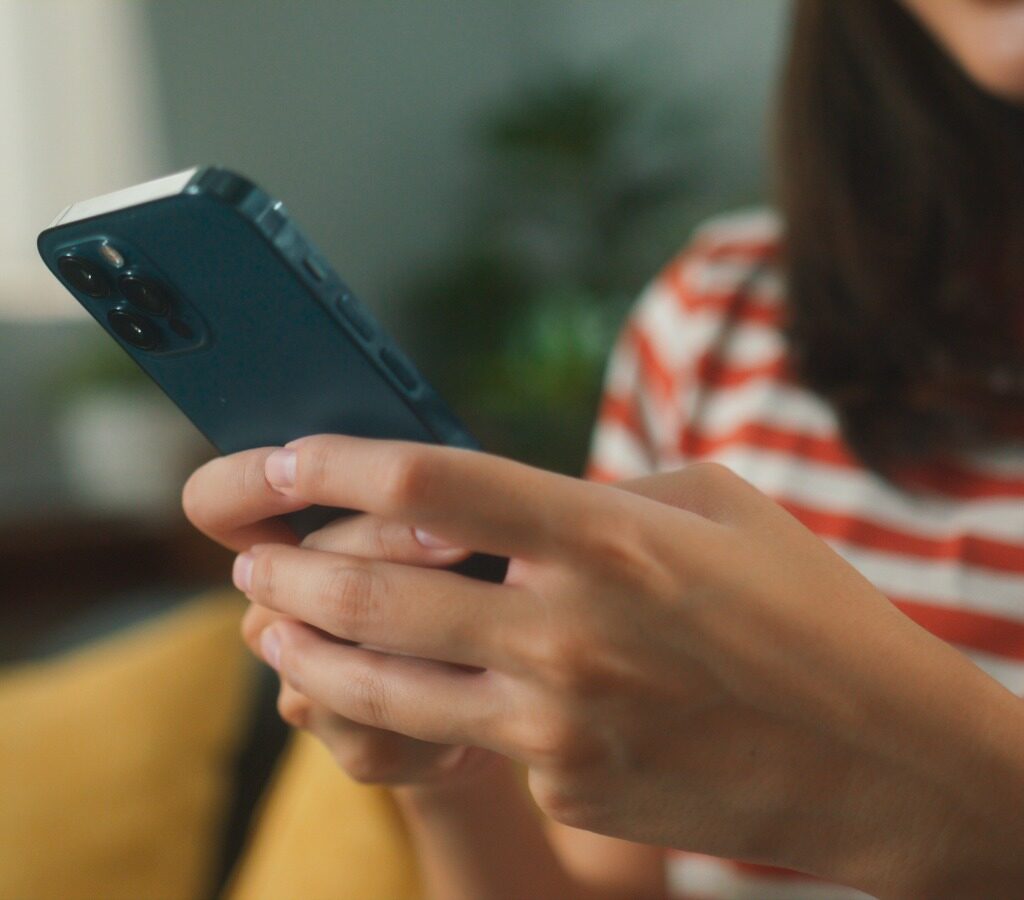 Imagen das maos de uma mulher usando o telefone para digitar