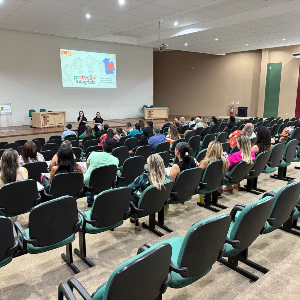 Imagem mostra auditorio com pessoas e apresentacao do projeto protecao integrada no datashow