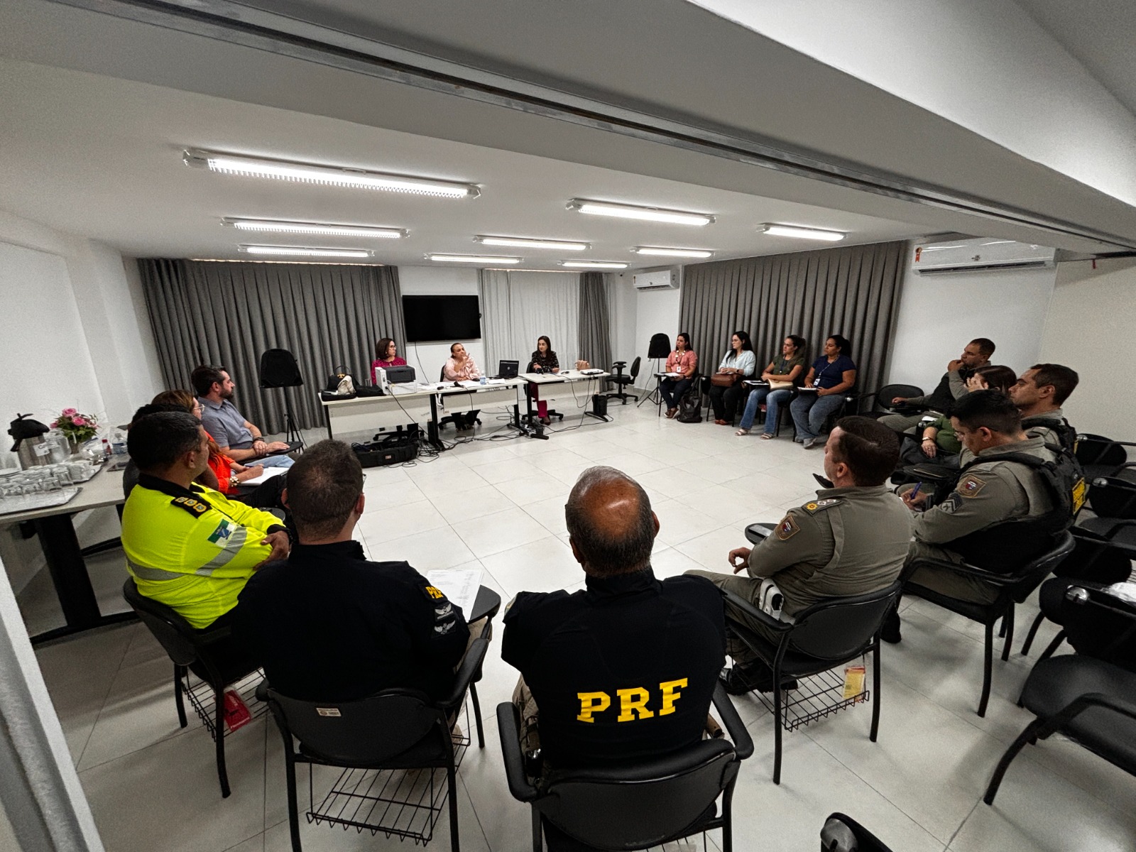 Pessoas sentadas em uma sala participando de uma reunião