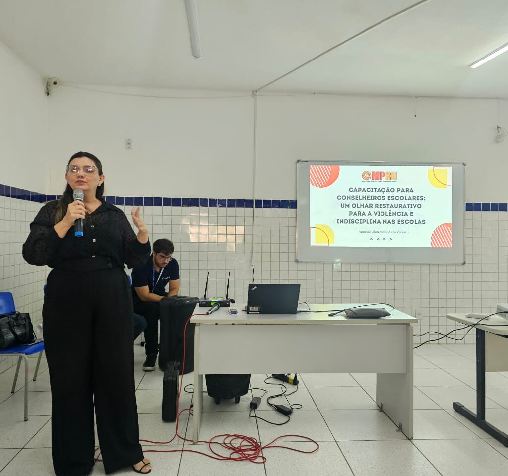 Imagem mostra palestrante em auditório falando sobre estratégias para lidar com a violência nas escolas