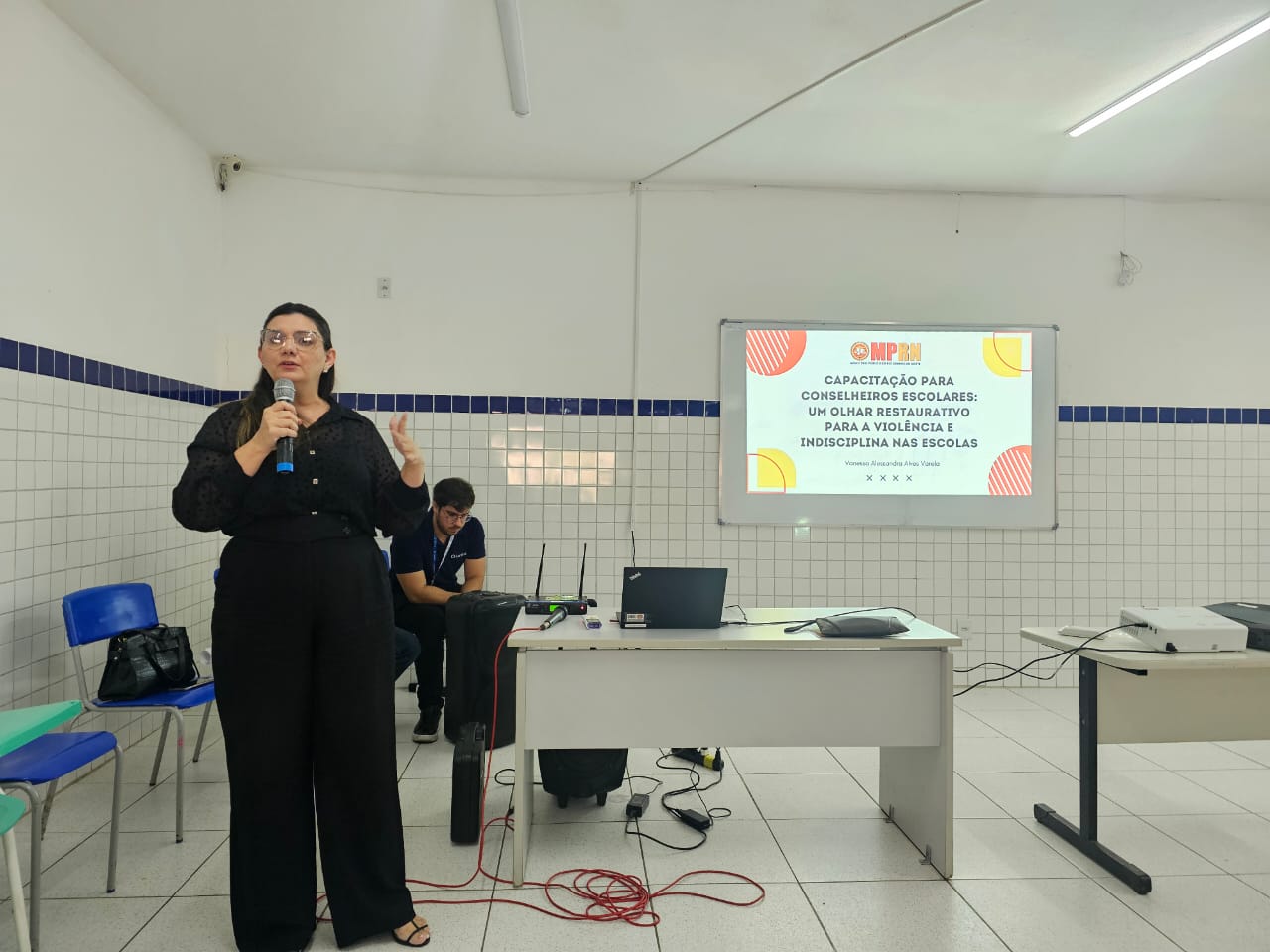 Imagem mostra palestrante em auditório falando sobre estratégias para lidar com a violência nas escolas