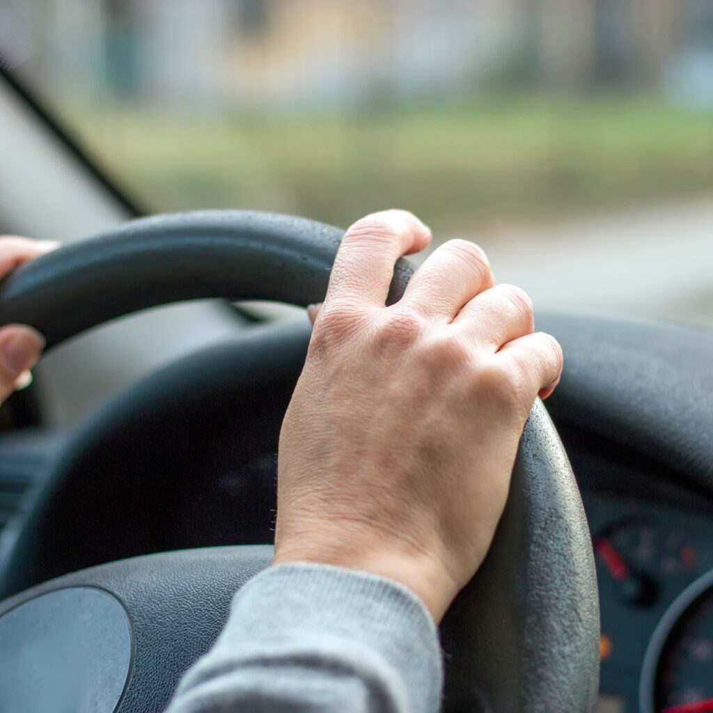 imagem de pessoa com as mãos no volante de um veiculo