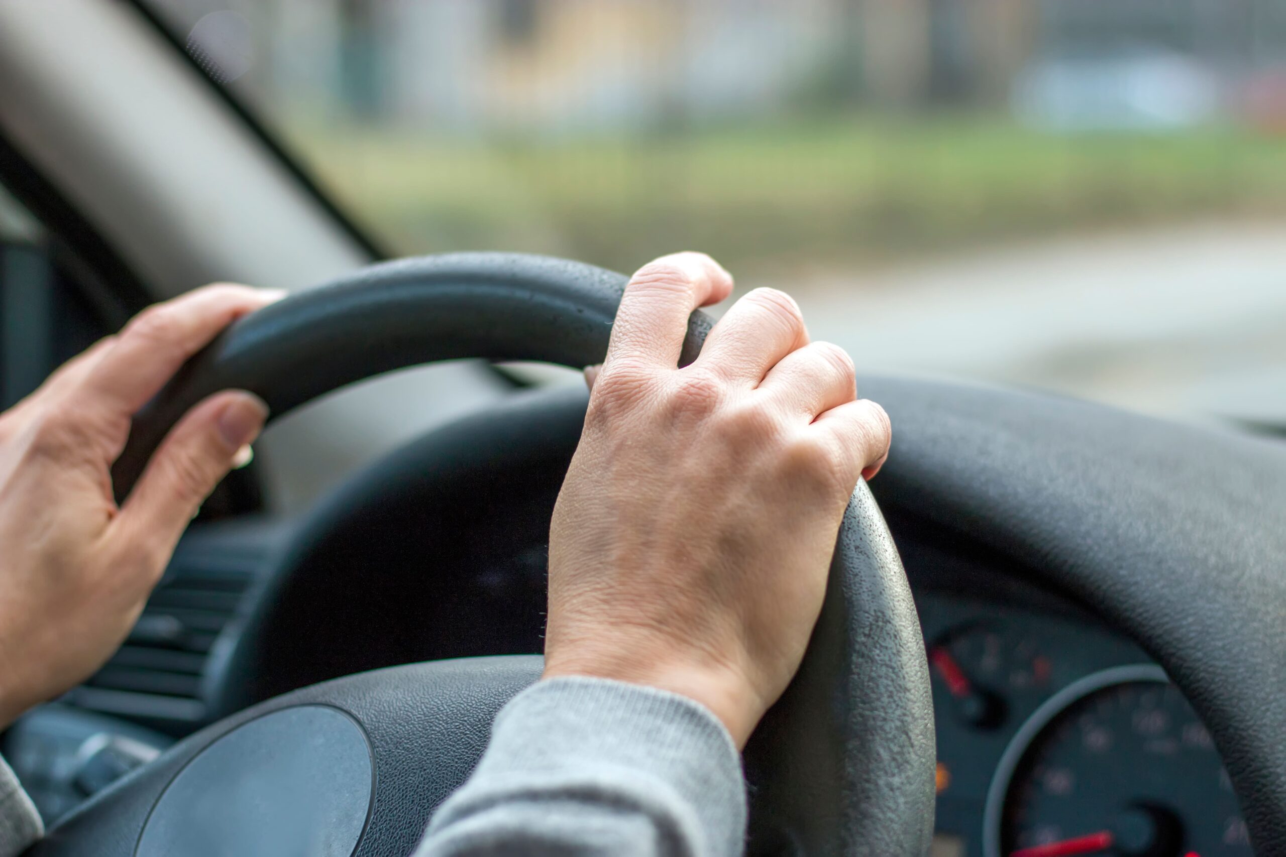 imagem de pessoa com as mãos no volante de um veiculo